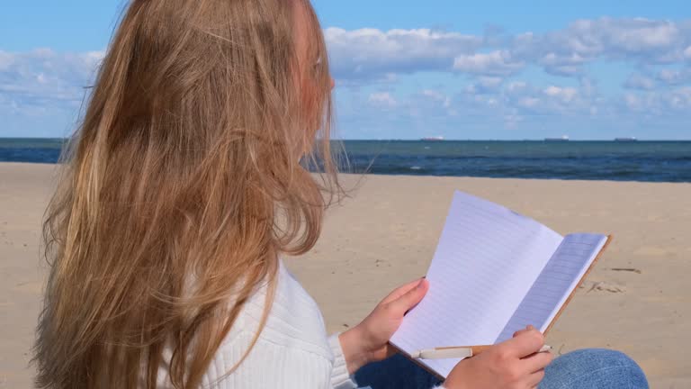 Young student study with notebook on beach next to sea ocean view. Writing gratitude journal self reflection self discovery self discovery, journal, self reflection, creative writing, self growth, personal developmentDrinking coffee and eat croissants. O