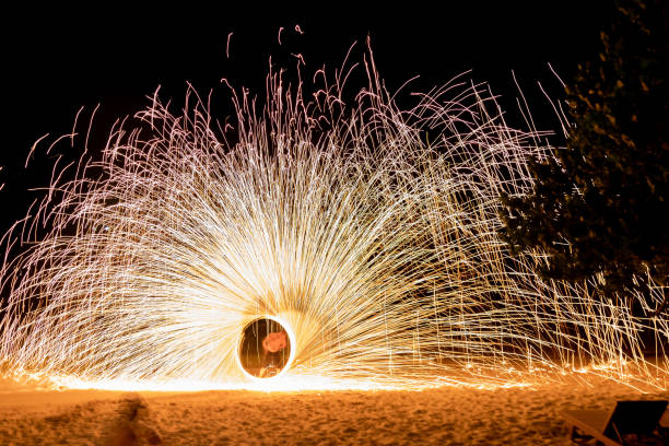 istock Glowing sparks shower from spinning steel wool on the beach. 1499431705