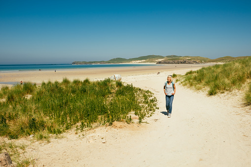 Woman walking on Balnakeil Beach beside the village of Durness on the north coast of Scotland. Part of the North Coast 500 road trip.