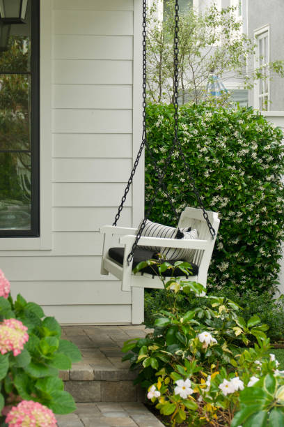 Colorful and modern bohemian boho outdoor front porch decoration with seating and a plant. The house is red brick and traditional.