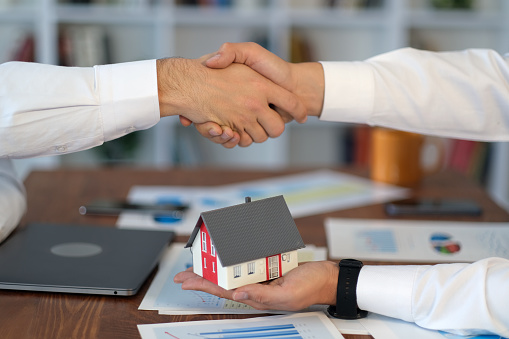 Sale agent and customer are handshaking and signing agreement
