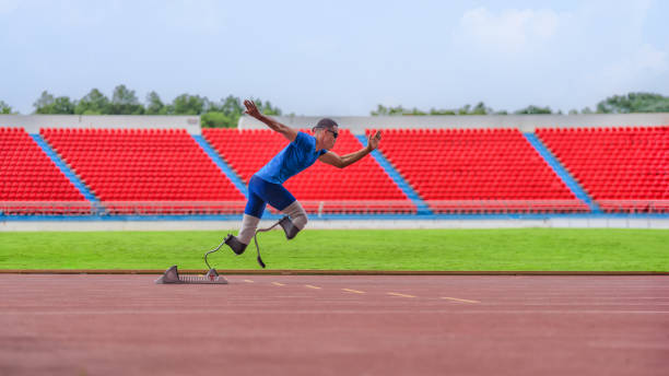 istock Asian male athlete, prosthetics user, sprints off from block start, powering his practice run on stadium track 1499449542