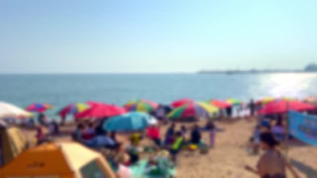 Blurred, people on vacation with parasols and tents on the beach