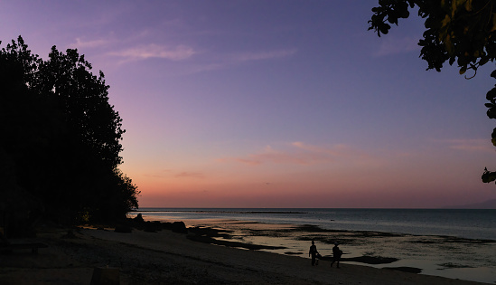 Sunset over the beach in sekotong as fishermen return home in indonesia