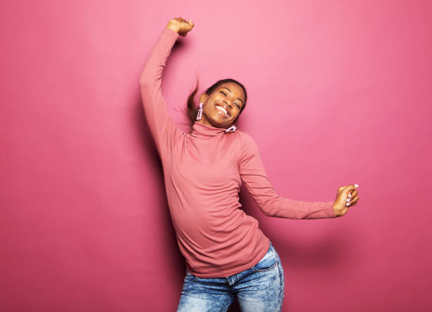 young afro woman wear casual clothes dancing looking empty space isolated pink color background stock photo