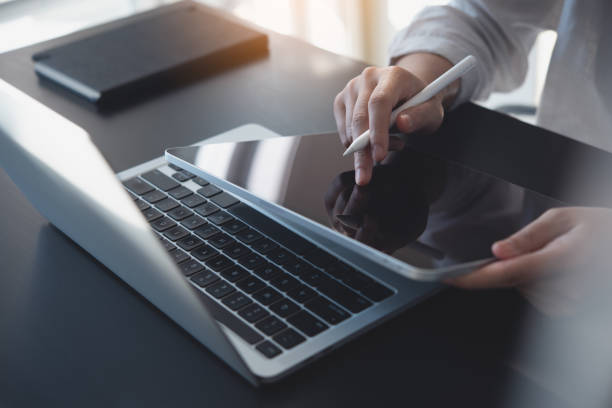 istock Close up, woman using digital tablet, finger touching on screen and working on laptop computer, surfing the internet on office table, online working, business and technology, internet networking, E-learning 1499460964