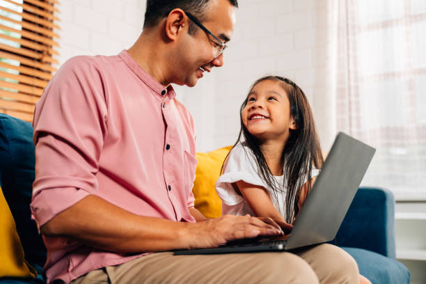 istock Father using laptop playing with daughter in living room 1499464344
