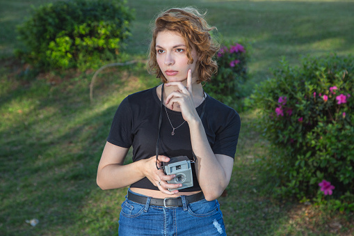 young woman holds an old camera in a park
