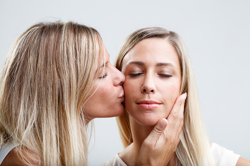 Two young blonde women comforting each other with tender kisses and caresses. Symbolizes relaxation, well-being, and mental care