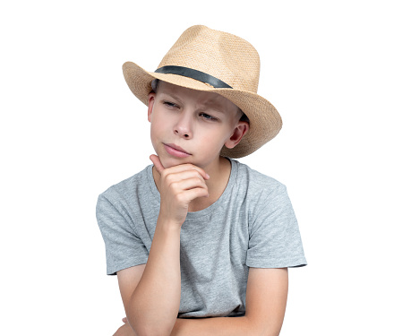 Portrait of a thoughtful teenager in a man's straw hat, isolated on a white background. File contains a path to isolation.