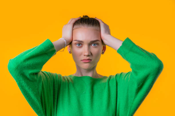 istock Woman afraid of something, she in shock on yellow backdrop.Holding head 1499472855