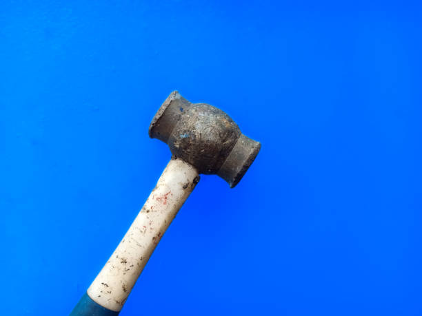 istock Old sledgehammer with white plastic  handle on blue metal background. Bronze sledgehammer to prevent spark. 1499474413