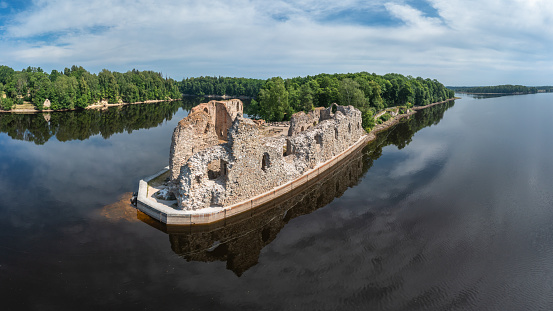 Aerial view of Koknese medieval castle ruins on the bank of Daugava river. Koknese Castle dating from the 13th century. The castle was situated on a high bluff overlooking the Daugava river valley. In 1965 a hydroelectric dam was built downriver, creating a reservoir That partially submerged flooded the castle and the surrounding valley.