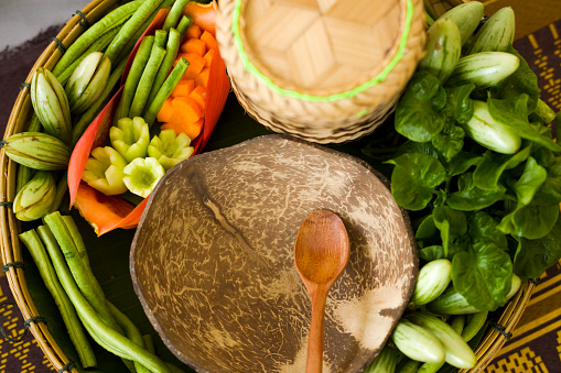 Coconut plate with wooden spoon and thai vegetables