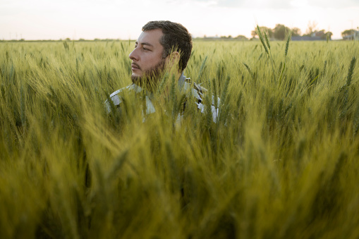 young adult man in hidden wheat field looking to the side at sunset. #uniqueSSelf