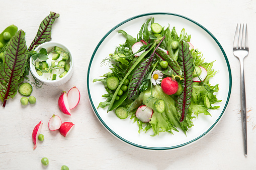 Vitamin spring salad. Salad of fresh vegetables and herbs.  Concept of healthy eating. Vitamins for immunity. Food for vegetarians on a white background. Top view.