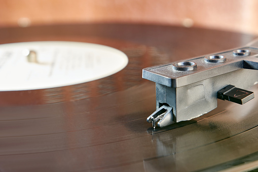 During playback of a music recording, the needle is lowered to the surface of the record. Audio equipment of the past.