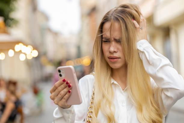 Surprised young woman use smartphone loses, bad news, fortune loss, fail outdoors in city street Blonde young woman use smartphone typing browsing, loses becoming surprised sudden lottery results, bad news, fortune loss, fail. Teenager girl walking in urban city street outdoors. Town lifestyles money cry stock pictures, royalty-free photos & images