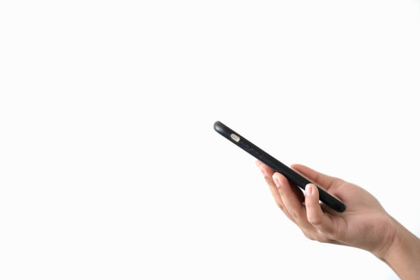 Woman hand holding black mobile phone on white background. Isolated hand using smartphone. Online and wireless technology concept on white background.