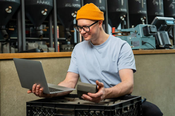 istock Coffeemaker using laptop in coffeshop accepts new cooffee beans. 1499487605