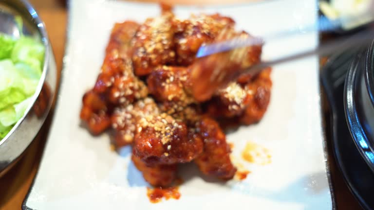 Close up using a chopstick to picking Korean spicy fried chicken.