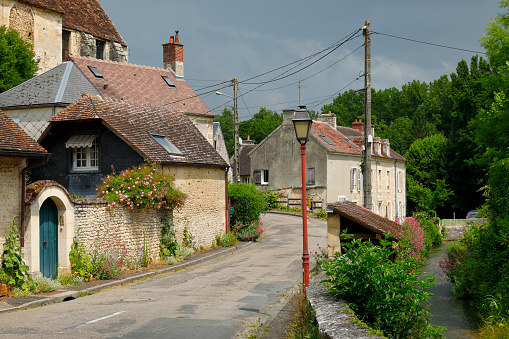 Street with historic buildings and a stream on the outskirts of Falaise