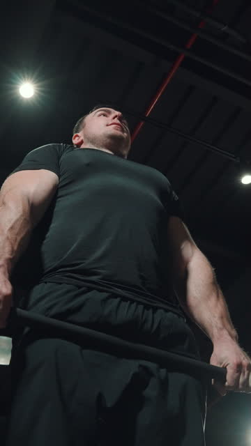 Vertical Screen: Bodybuilder lifting barbell in dark gym