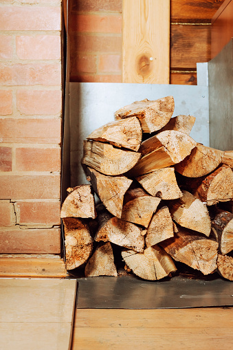 Stacked firewood near log wall of rustic house closeup. vertical.