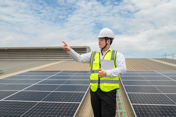 Engineer checking installation of solar panels installed on factory roof, checking installation of solar panels. Asian engineer records inspection data on tablet, supervising solar panel installation. ingeniero de verificación de la instalación de paneles solares instalados en el techo de la fábrica, verificando la instalación de paneles solares. ingeniero asiático registra los datos de inspección en tabletas, supervisando la instalación del pane