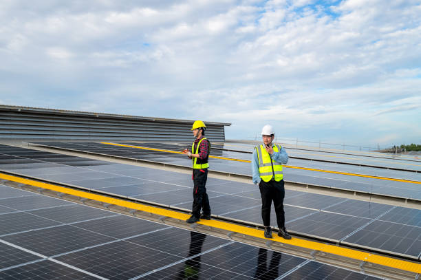 Asian engineer inspect installation of solar panels installed on factory roof, with technicians, foremen recording inspection data on tablet. Engineer to command, control work with radio communication ingeniero asiático inspecciona la instalación de paneles solares instalados en el techo de la fábrica, con técnicos y capataces que registran los datos de inspección en tabletas. ingeniero para comandar, controlar el trabajo con comunicación por radi