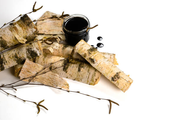 istock Birch tar or pitch in a jar and birch tree bark on white background. Wood tar. Liquid mineral tar from birch bark 1499493687