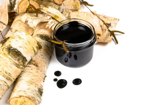 istock Birch tar or pitch in a jar and birch tree bark on white background. Wood tar. Liquid mineral tar from birch bark 1499493691
