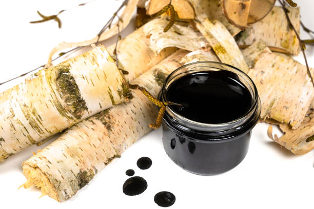 istock Birch tar or pitch in a jar and birch tree bark on white background. Wood tar. Liquid mineral tar from birch bark 1499493693