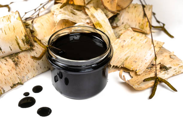 istock Birch tar or pitch in a jar and birch tree bark on white background. Wood tar. Liquid mineral tar from birch bark 1499493711
