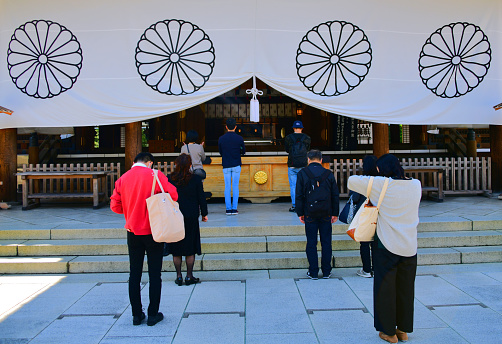 Tokyo, Japan: wooden haiden of Yasukuni Shrine ('靖国神社'), Peaceful Country Shrine - Shinto shrine founded by Emperor Meiji in 1869 - people paying homage to the spirits of those who died in service of Japan - curtain with chrysanthemum seal pattern (Imperial Seal of Japan) - Chiyoda-ku. Open access, no entrance fee site.