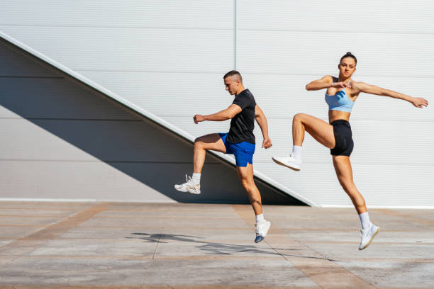 istock Fit couple moving and jumping. They are stretching and warming up their bodies before training, on a beautiful sunny day 1499497690