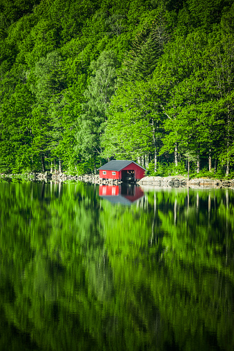 Red boathouse on the shore of a lake in Norway