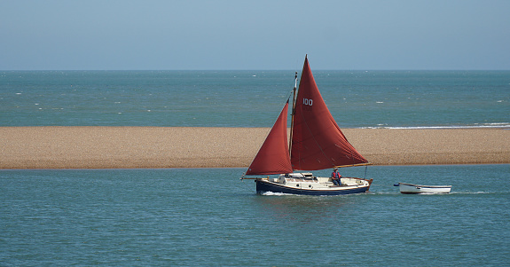 Felixstowe, Suffolk, England - June 14, 2023: Vintage Red sailed Yacht entering the river Deben estuary at Felixstowe Ferry.