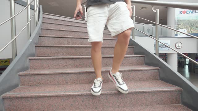4K footage of man in white shorts and sneakers going down a marble staircase. Camera follows steps of passenger stock video.