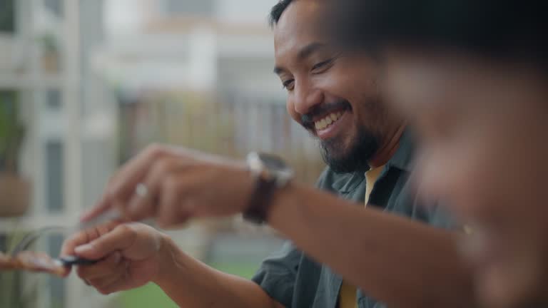 Close up hands of asian man serving meat to friends and family at dinner table.