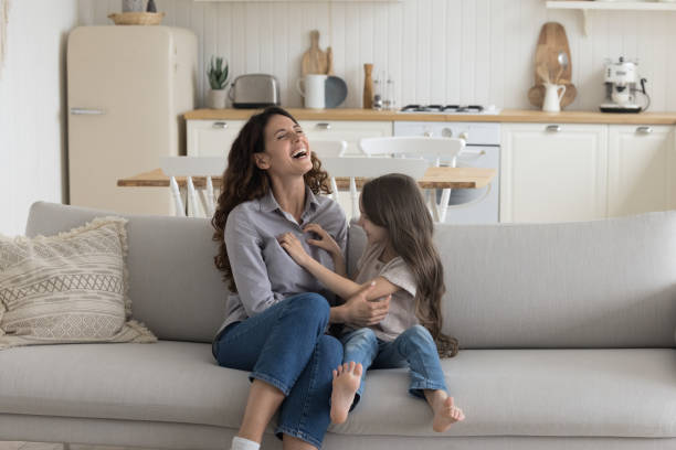 istock Cheerful excited mom and kid girl playing on sofa 1499522830