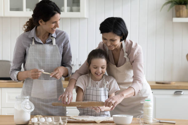 おばあちゃんとお母さんが家で焼くのを手伝うポジティブな女の子 - grandmother senior adult family domestic kitchen ストックフォトと画像