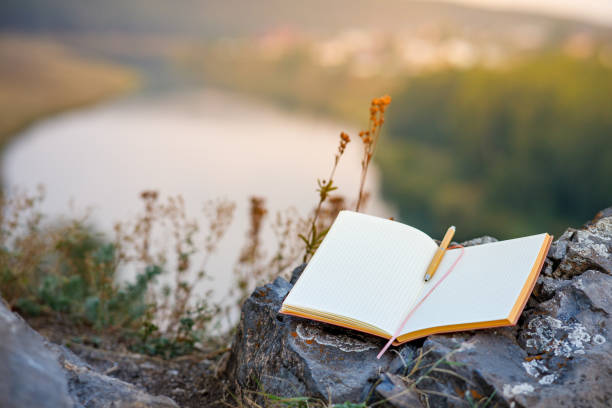 an open empty book with a fountain pen outdoors, the background is a blurred river and forest - dagbok bildbanksfoton och bilder