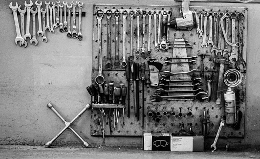 Creatively arranged tools on the wall of the workshop- screwdrivers, keys, gloves, spare parts