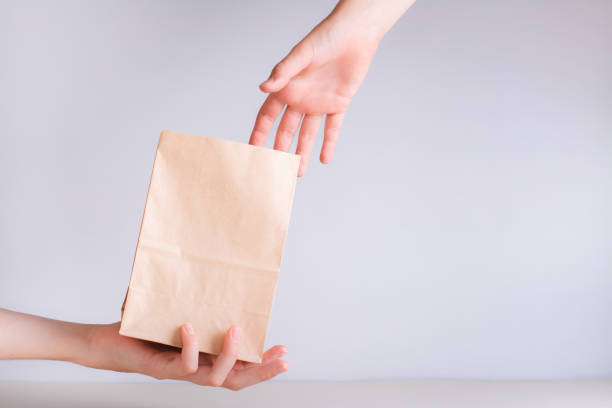 istock Hand giving a disposable zero waste paper bag to another hand 1499526595