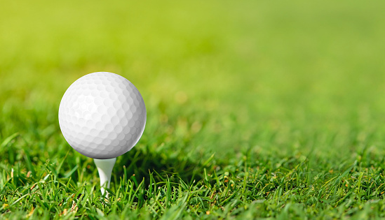 Golf ball on grass in green background. Banner for advertising with copy space. Sport and athletic concept.