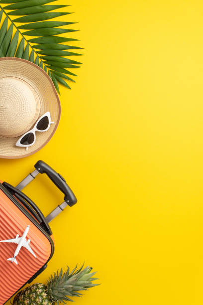 istock Summer getaway inspiration. Vertical top view composition featuring suitcase, small airplane replica, eyeglasses, hat, palm leaf against striking yellow backdrop. Perfect for text or promo content 1499544884