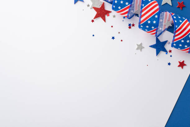 Commemorating Independence Day in the USA. Top-down view of symbolic party elements: swirling ribbon, glittery stars, glimmering confetti. Two-toned white and blue backdrop with space for text or ad conmemoración del día de la independencia en los estados unidos. vista de arriba hacia abajo de os simbólicos del partido: cinta giratoria, estrellas brillantes, confeti brillante. fondo blanco y azul de dos tonos con espacio para texto o anuncio