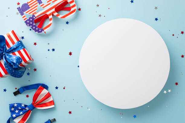 istock Setting the mood for American Independence Day. Top view party decorations featuring confetti, party eyeglasses, bow-tie in national flag colors, giftbox, on a blue backdrop with circle for text or ad 1499545540