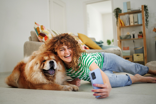 Smiling woman taking selfie with her cute Chow dog